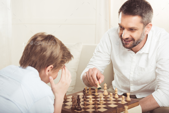 Premium Photo  Smiling little boy joying playing chess on wooden