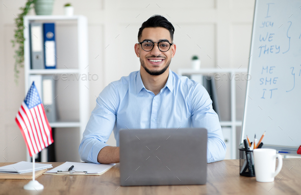 Male foreign languages tutor teaching English online using laptop at home  office Stock Photo by Prostock-studio