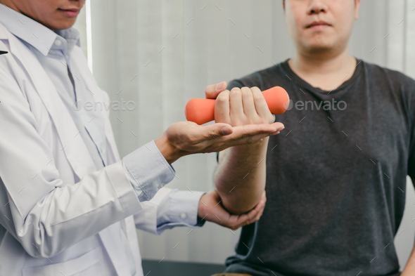 Asian physiotherapists are helping patients lift dumbbells for arm recovery.