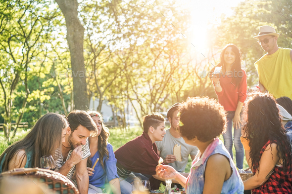 Happy friends eating and drinking red wine at picnic party outdoor - Stock Photo - Images