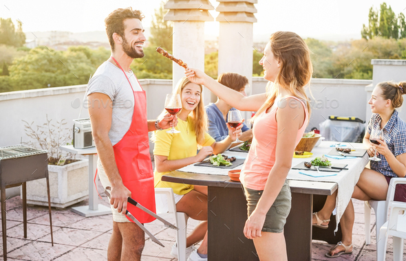 Happy friends eating and drinking red wine at barbecue party - Stock Photo - Images