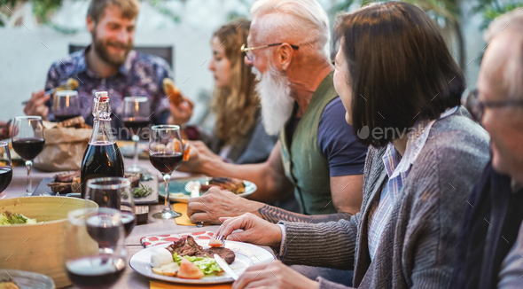 Happy family eating and drinking wine at barbecue dinner outdoor - Stock Photo - Images