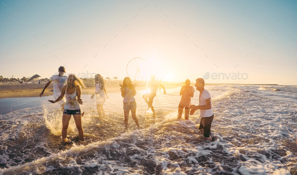 Happy friends having fun on the beach at sunset - Stock Photo - Images