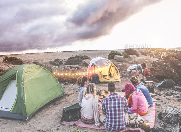 Happy friends doing barbecue picnic camping in the desert at sunset - Stock Photo - Images