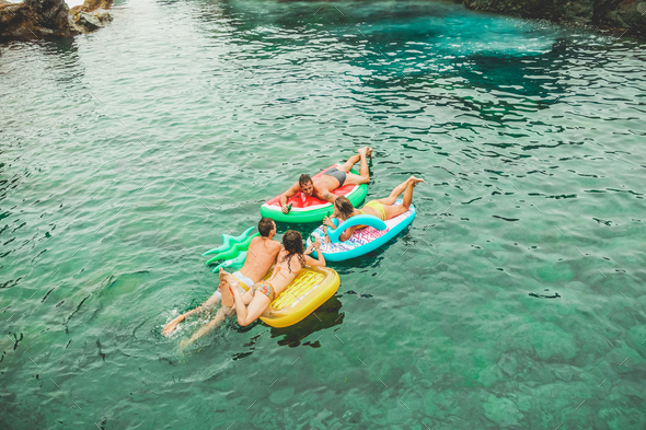 Happy friends floating with lilos mattress inside sea natural pool - Stock Photo - Images