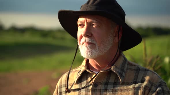 Close up portrait of senior caucasian good looking wise man farmer in a hat looking at the side, tur alt