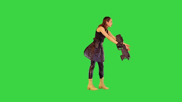 Gamecharacter Girl with a Gun Takes an Aim and Starts Shooting on a Green Screen Chroma Key