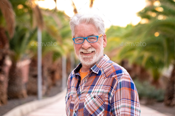 Portrait of attractive senior man white-hair and beard looking at camera. Standing outdoor - Stock Photo - Images
