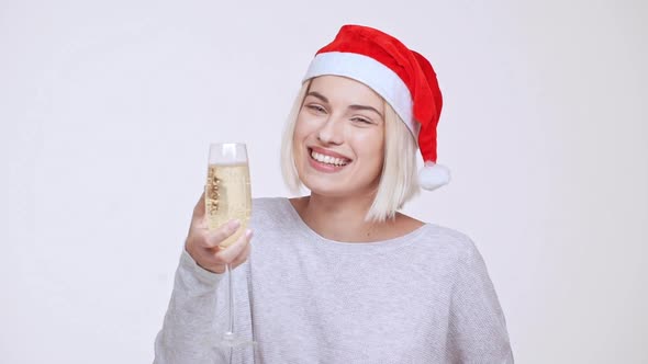 Young Beautiful Blonde Girl in Christmas Hat Holding Glass of Wine Toasting Winking Showing Thumb Up alt