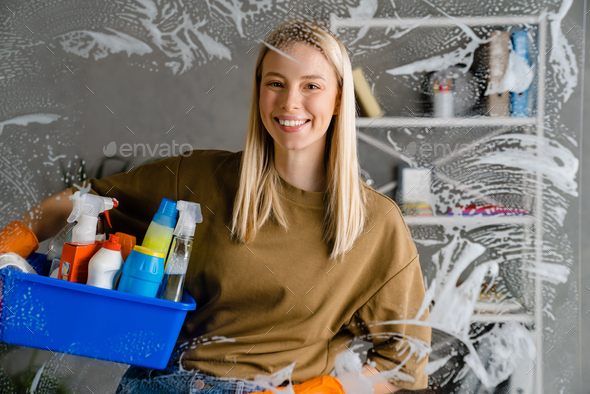 Woman holding basket with cleaning supplies Stock Photo by