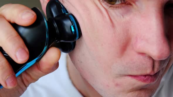 A man shaves with an electric razor close-up. Smooth shaving of light bristles. Slow Motion alt