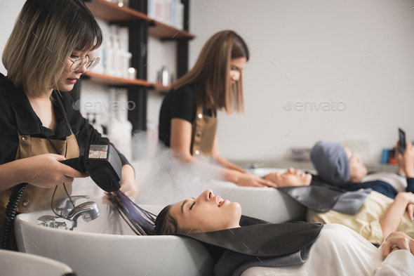 professional hairdresser working to water washing hair clean with woman client in beauty salon