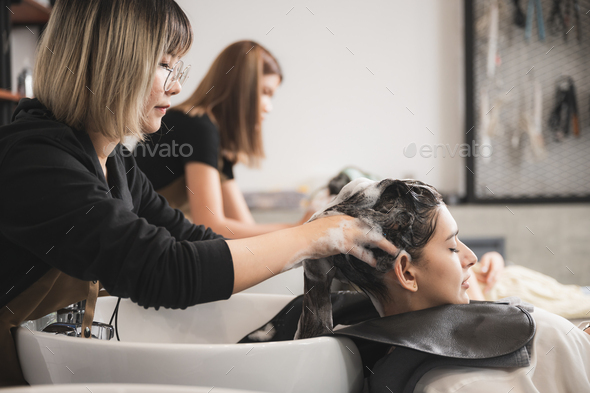 professional hairdresser working to water washing hair clean with woman client in beauty salon