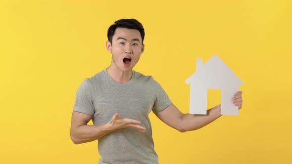 Portrait of smiling young asian man showing house symbol