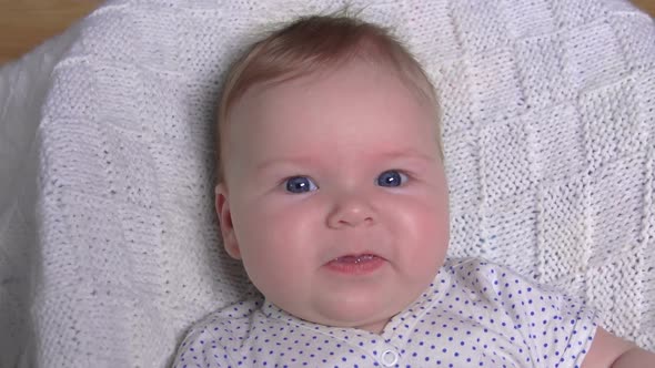 Little Cute Blue-eyed Baby on a White Blanket Is Laughing Happily  alt