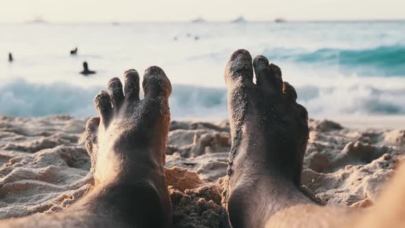 POV Feet of Young Man Lying on Sandy Beach By the Ocean During Sunset Zanzibar alt