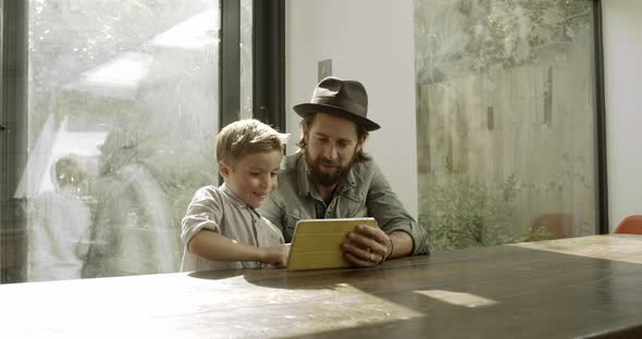 Father and son using digital tablet in domestic room 