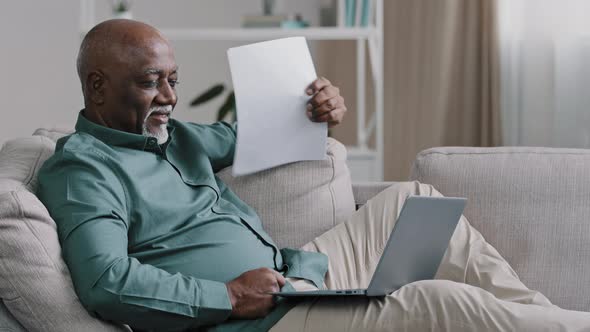 African American Old Senior Mature Man Waving Paper Document Suffering From Summer Heat at Home alt