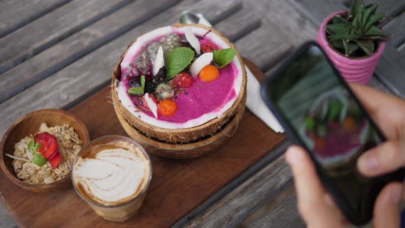 Top View of Vegan Breakfast of Smoothie Coconut Bowl Served on Wooden Board with Dairy Free Latte alt