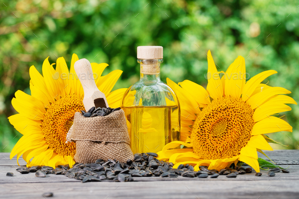 Bottle of sunflower oil and sunflower with seeds on wooden table - Stock Photo - Images