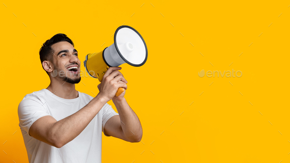 Excited arab guy speaking loud, using megaphone on yellow