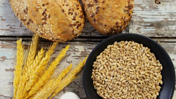 Wheat grains with bread buns, oats and spoon full of flour alt
