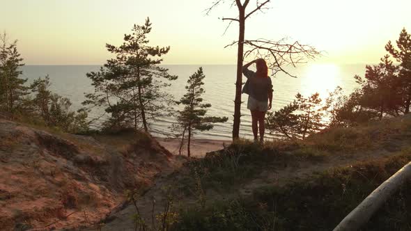 Drone Flight From Backside To Sea Horizon: Young Woman Enjoys Beautiful Scenic Sunset at Baltic Sea alt