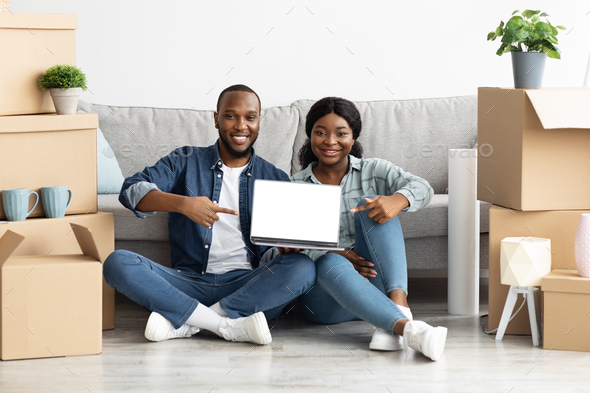 Black Spouses Pointing At Laptop With Blank Screen At Their New Home