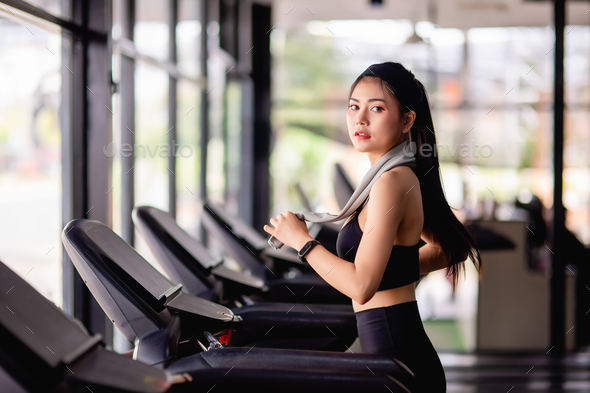 Young healthy woman on treadmill workout in gym