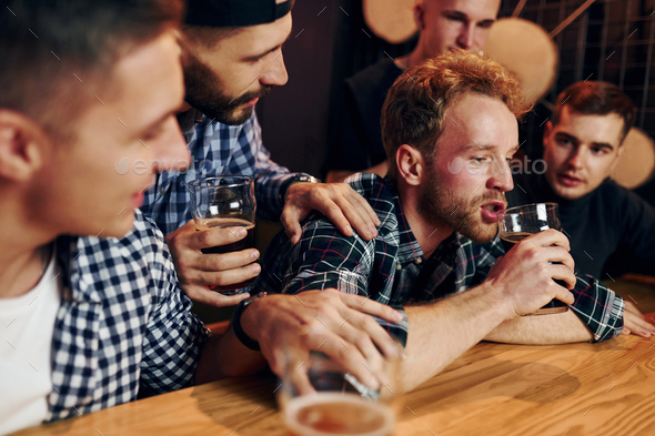 Sad man feels bad. Group of people together indoors in the pub have fun ...