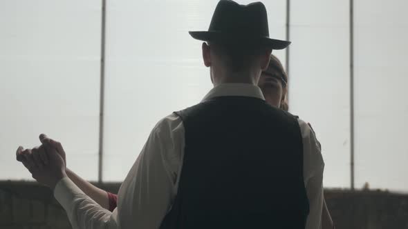 Man in Fedora Hat, Classical Suits and Woman in Style Cloth Dancing in Dirty Place. alt