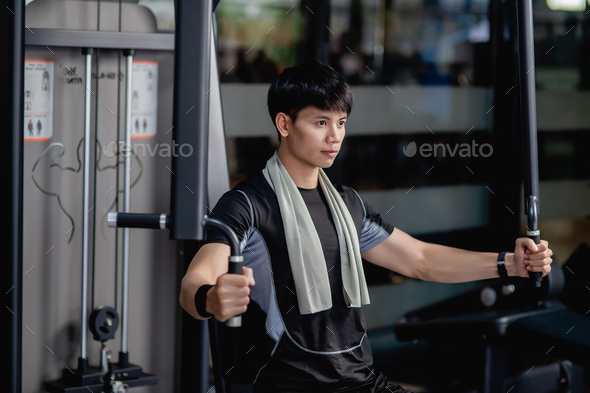 Young sportman doing machine chest press exercise in modern gym