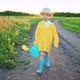 Baby Boy Walks Along Rural Country Road Through Field in Rubber Boots and Raincoat with Watering Can - VideoHive Item for Sale