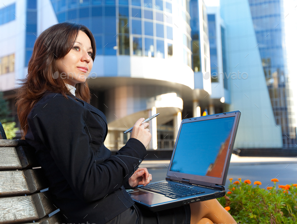 Businesswoman sitting on bench in park with notebook