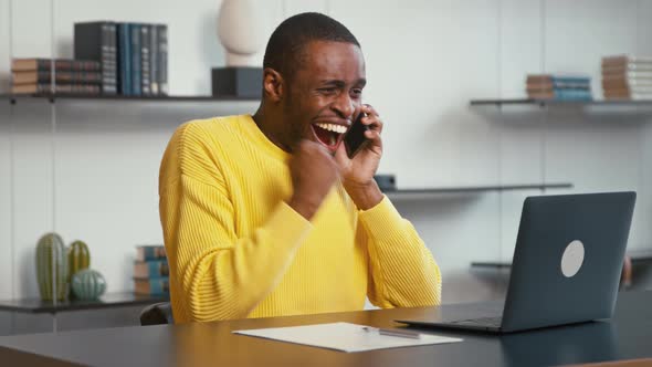 Smiling male talking on the phone while sitting at the desk alt