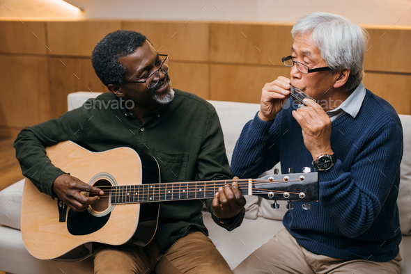 senior friends playing music with acoustic guitar and harmonica