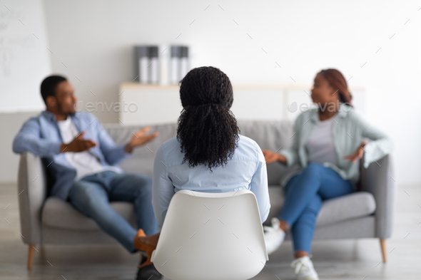 Marital therapy. Psychologist sitting with her back to camera during appointment with unhappy black
