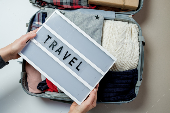Woman hands with travel board on the background of Open suitcase packed