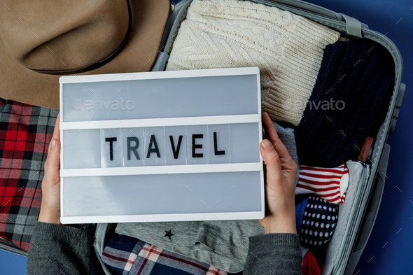 Woman hands with travel board on the background of Open suitcase