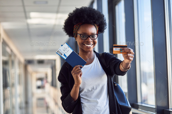 Young african american female passanger in casual clothes is in airport holding tickets
