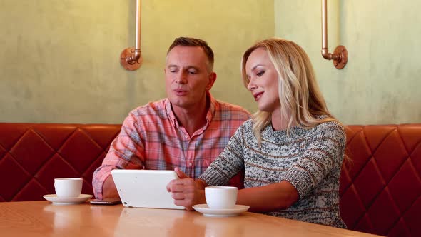 Couple using digital tablet while having coffee 4k alt