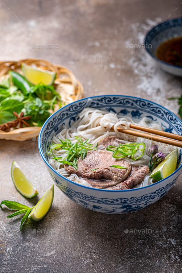 Close view of pho bo in traditional bowl garnished with basil