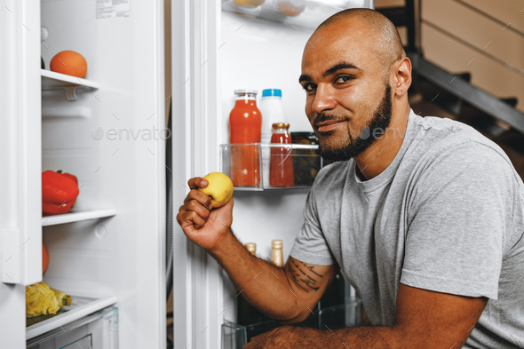 African american man taking food from a fridge in his house