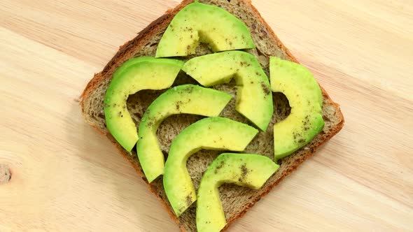Sandwich with slices of avocado with pepper and salt top view alt