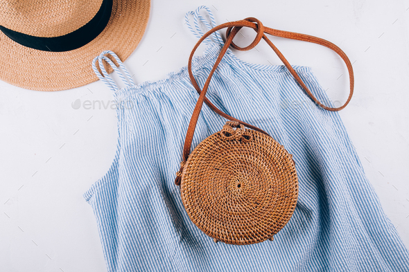 Blue summer dress, organic round bag, straw beach hat. Casual clothes for summertime. Flat lay