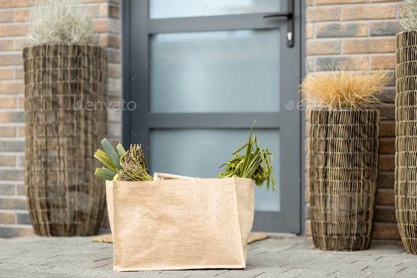 Shopping bag with fresh products from grocery on the doorstep at the front door of house.