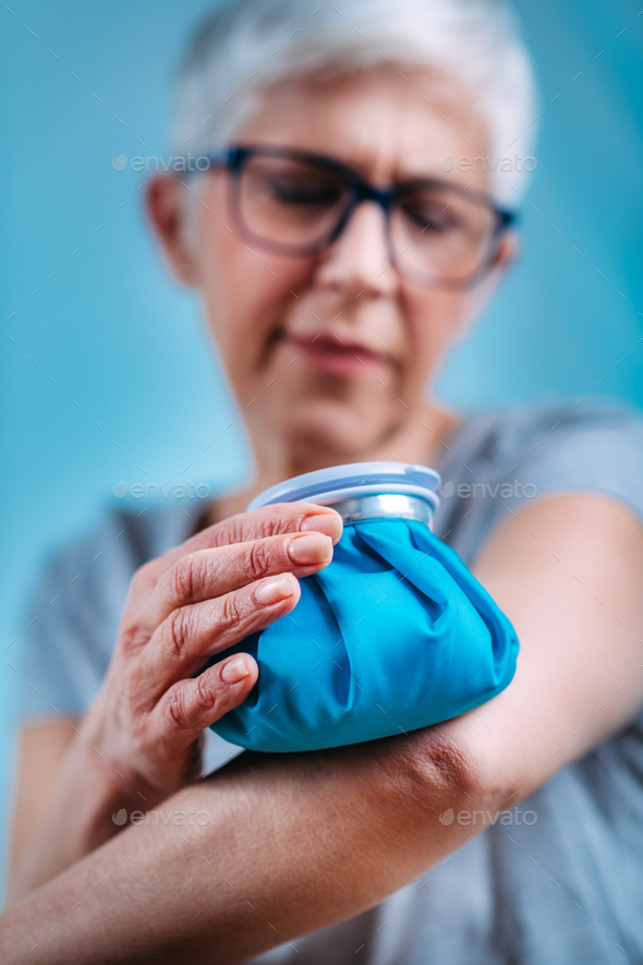 Elbow Pain Treatment. Senior Woman Holding Ice Bag Compress on Painful Elbow
