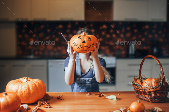 Frightful Treats on the way. Portrait of housewife in the Halloween decorated kitchen holding a big - Stock Photo - Images