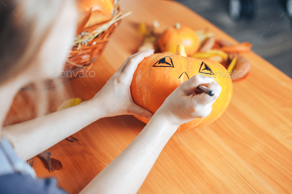 Preparation for Halloween: woman hands paint orange pumpkin with black paint. Closup. Holiday - Stock Photo - Images
