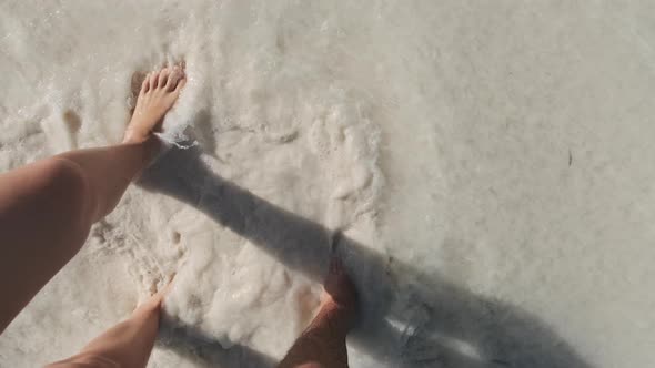 POV Legs of a Young Couple Walking By White Sand and Surf Waves of Ocean Shore alt
